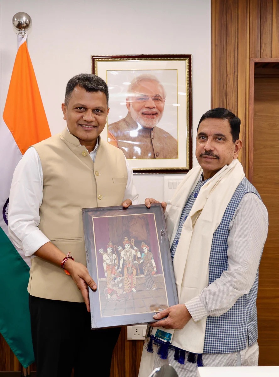 Pralhad Joshi and a visitor holding a framed painting together in an office