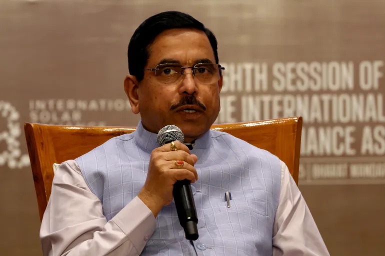 Pralhad Joshi speaking into a microphone, seated, in front of an International Solar Alliance Assembly backdrop
