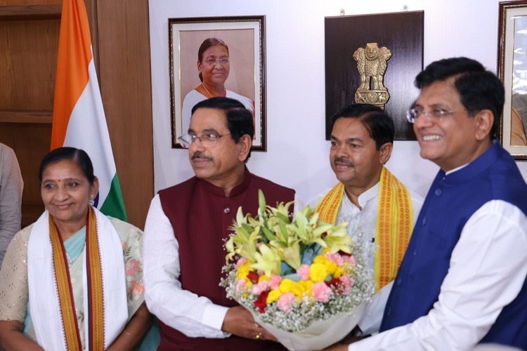 Pralhad Joshi receiving a bouquet of flowers in an office, with three other people beside him