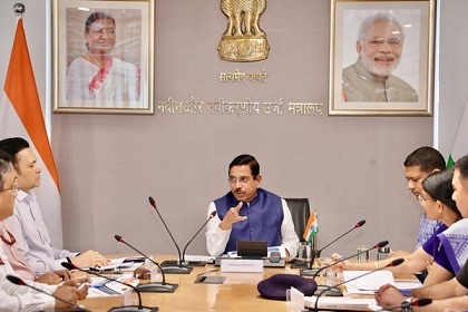 Pralhad Joshi chairing a meeting with officials seated at a table beneath the name of the Ministry of New and Renewable Energy in Hindi