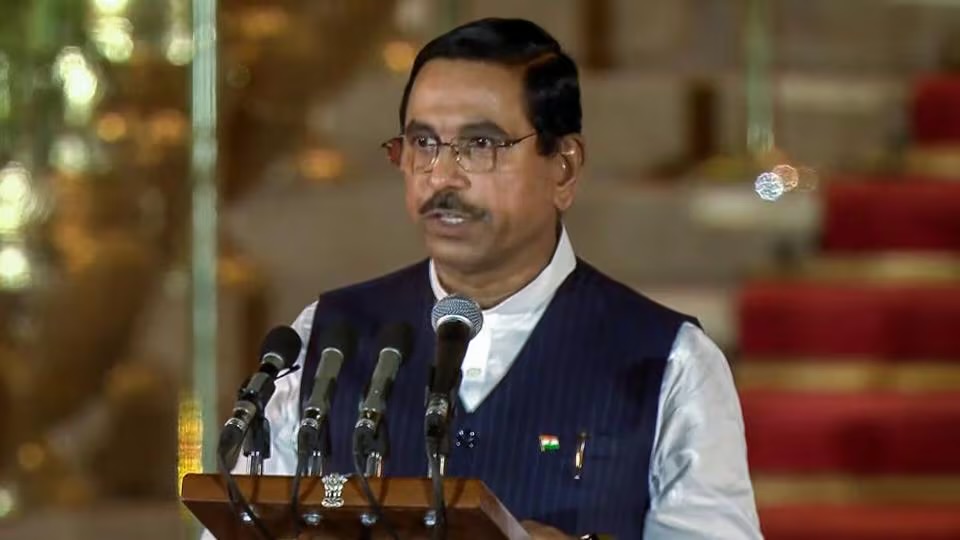 Pralhad Joshi speaking at a lectern with microphones during the swearing-in ceremony at Rashtrapati Bhavan