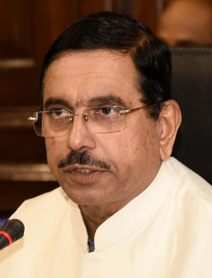 Close portrait of Pralhad Joshi wearing a cream kurta, speaking at a microphone